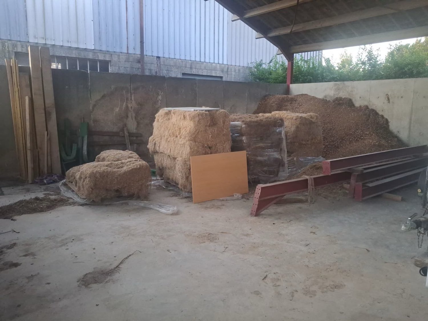 Fourrage et plaquettes de bois entreposés dans un hangar agricole avant leur séchage